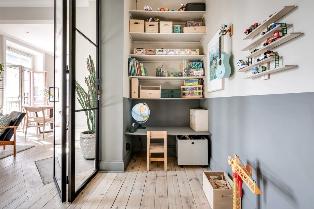 In deze leuke en speelse kinderkamer is de wandplank en het bureau in dezelfde kleur geschilderd als de muur.